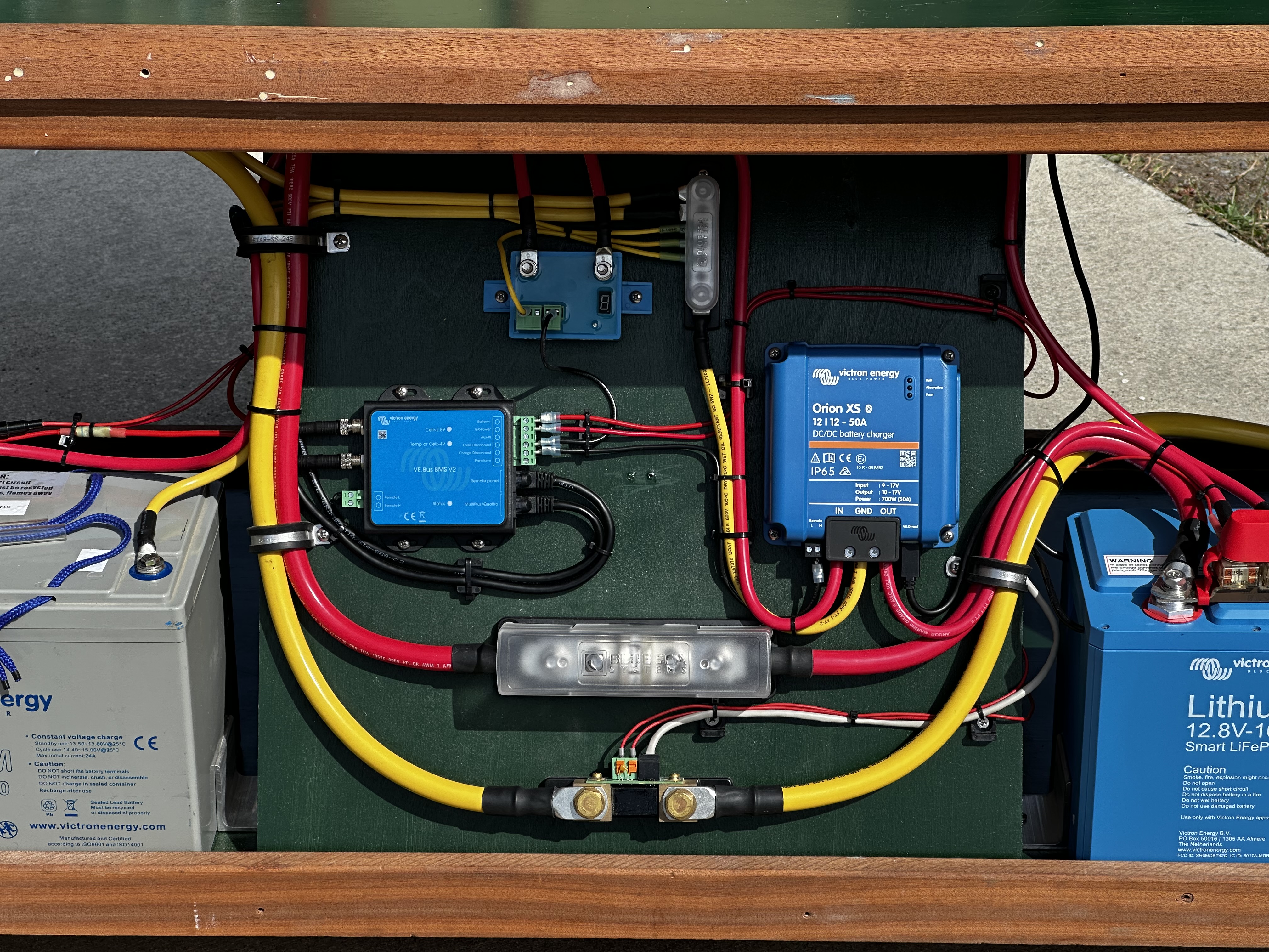 Battery compartment showing Victron AGM starter battery, Victron LiFePO4 house battery, VE.Bus BMS, Orion XS DC-DC charger, and main fusing