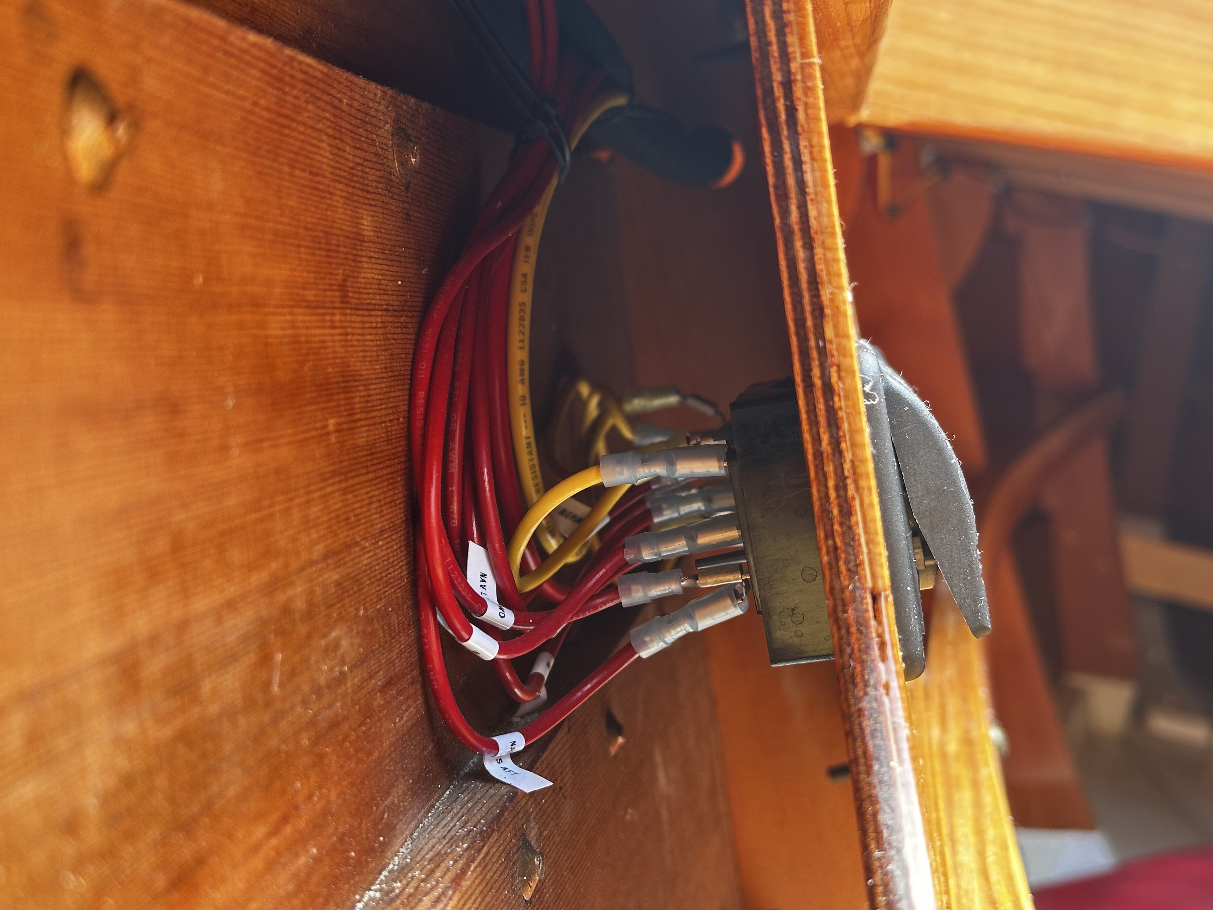 Labeled conductors routed behind the console panel terminating at the battery switch — showing clean organization and serviceable layout